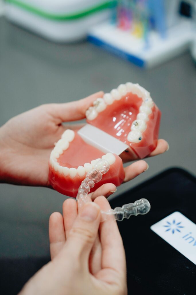 A close-up of hands holding a dental mold and Invisalign clear aligner, perfect for orthodontic care visuals.